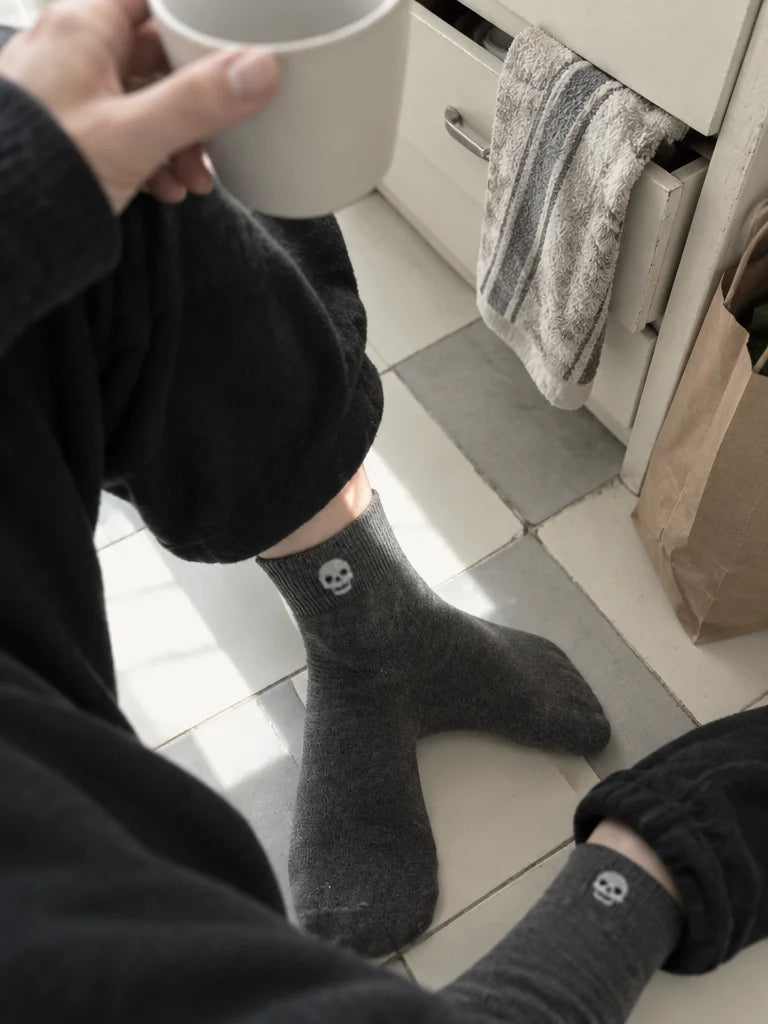 A customer's own photo angled down at her feet in a small kitchen: the charcoal mid-calf socks from
